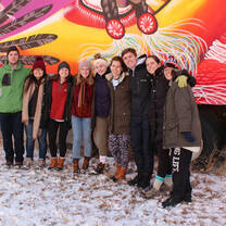 A group posing for a photo outside a colorful truck.