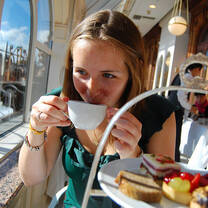 Woman student drinking tea with a tower of pastries in front of her 