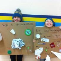 Two kids handling a cardboard with their art made