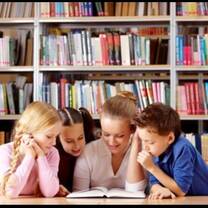 woman reading story to three little kids