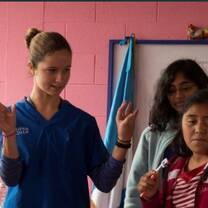 young lady in a blue scrub suit giving a lecture to group of young students