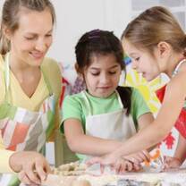 woman playing with 2 pretty girls while baking