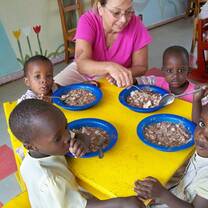 four black little boys being fed by a white woman