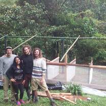 3 volunteers and Maricela proudly posing in front of just made composting structure