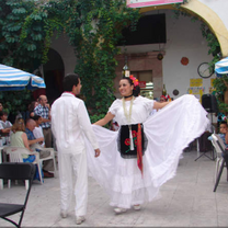 A pair in traditional costume dances outside a cafe.
