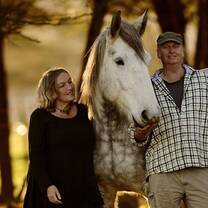old man and woman cuddling a white horse