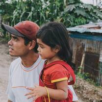 Man in hat carries little girl.