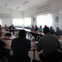 men and women are sitting on the long table and having a meeting