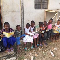local boys and girls reading books outside a house