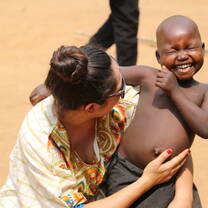 woman holding little African boy smiling really big