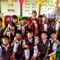 group of school children in uniforms with teacher holding art projects in Thailand