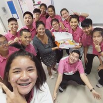 group of students in pink shirts with teacher holding Dunkin Donuts box of donuts