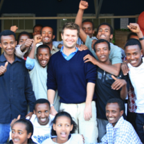 European Volunteer together with a group of teenagers smile to the camera 