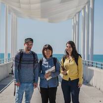 two women and a man standing in a middle of a bridge