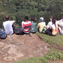 group of young men and women sitting on top of a mountain