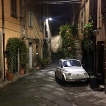 The city called Civita di Bagnoregio, located in the Lazio region like Viterbo, is known as the Dying City because it is located on a hilltop and is slowly falling apart. Picturesque Italian made white FIAT 500 in a hidden corner.