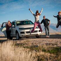Group of people jumping next to car
