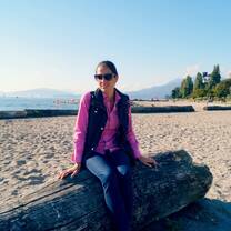 Girl sitting on log on beach