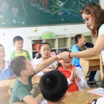 woman teaching handing to kid in a classroom 