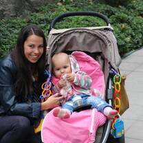 a woman wearing black leather jacket with a baby on a stroller beside her