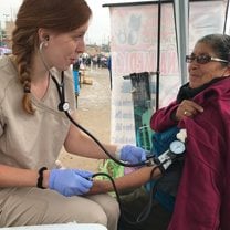 A kind lady rolling up her sleeve as I adjust the blood pressure cuff. 