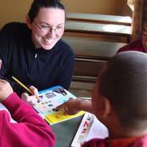Volunteer in Nepal looking at book with student