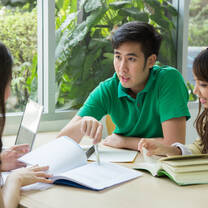 asian man reading from a book in a green shirt
