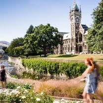 A couple young students walk on campus by a gothic building