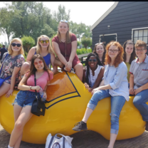 A group of friends poses in a giant, yellow clog in Zaans Schans, Netherlands