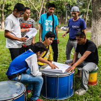 Youth deep in thought discuss strategies for responding to human rights violations next to some drums.