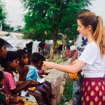 Volunteer from Italy distributing food to children in slums of Jaipur, India with The Tarzan Way