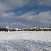 A river is covered by snow and complements the blue sky and white clouds.