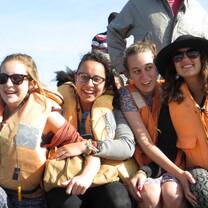 Students smiling and laughing together on a small boat. 