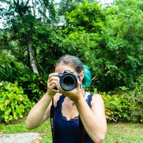 Girl holding Camera with a frog sitting on the lens.