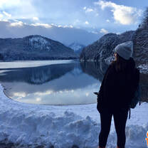 woman looking out over blue lake and mountain