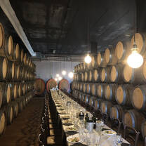 Long table set surrounded by wine-aging barrels in Italy.
