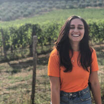 Woman smiling at a Tuscan vineyard.