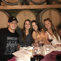 Happy people smiling over shared wine on their wine tour of Italy.