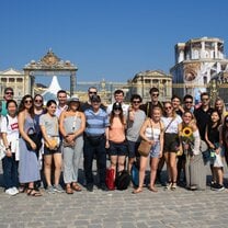 A group of male and female study abroad students smiling in a large European square.