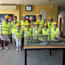 Students together for a group photo wearing vests and hardhats. 