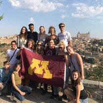 Students outside holding the UofM flag. 