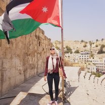 Me standing under a Jordanian flag on top of the Roman Amphitheatre in Amman, Jordan