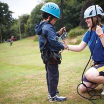 Camp staff assisting youth with rope climb