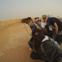 girls in desert taking selfie with camel