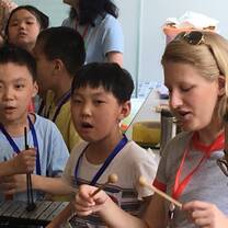 Two children play a xylophone with a college student