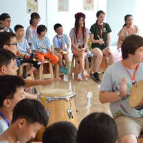 A group sits in a circle playing instruments