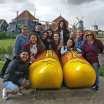 Students pose in a clog sculpture