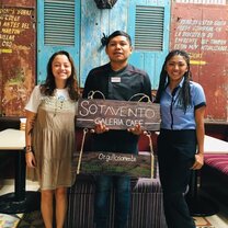 three people at small business holding sign 