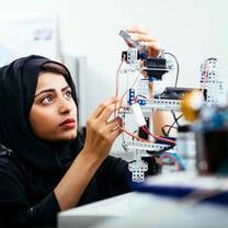 An inquisitive woman with a black headscarf tinkers with high tech gadgets in Khalifa University lab