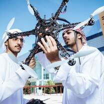 Two male Khalifa University students examine their large custom built 6 propellor drone
